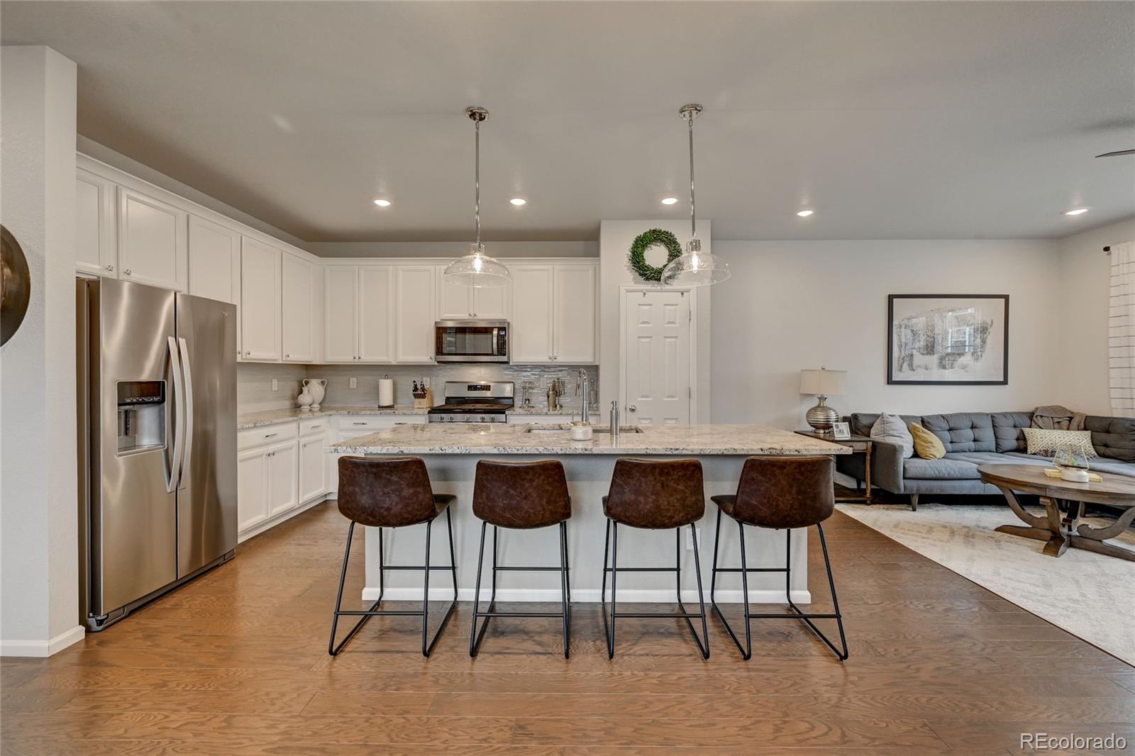 7203 Bedlam Drive Castle Pines, CO 80108 - Photo 8 of 39 a view of kitchen with refrigerator stove dining table and chairs