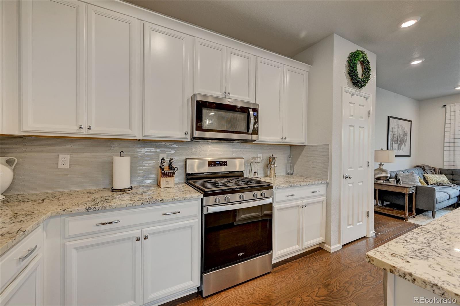 7203 Bedlam Drive Castle Pines, CO 80108 - Photo 10 of 39 a kitchen with granite countertop white cabinets and stainless steel appliances