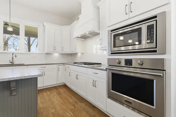 a kitchen with granite countertop white cabinets stainless steel appliances and a counter space