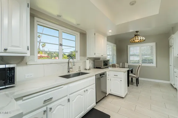 a large kitchen with kitchen island granite countertop a large window and white stainless steel appliances