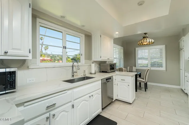 a large kitchen with kitchen island granite countertop a large window and white stainless steel appliances