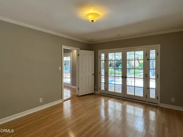 a view of an empty room with wooden floor and a window