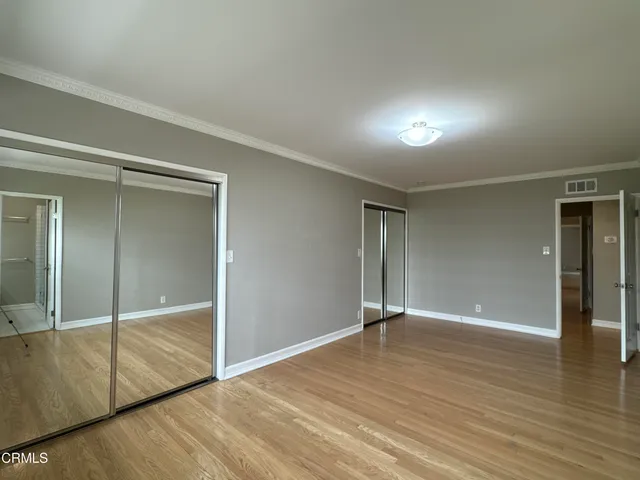an empty room with wooden floor mirror and windows