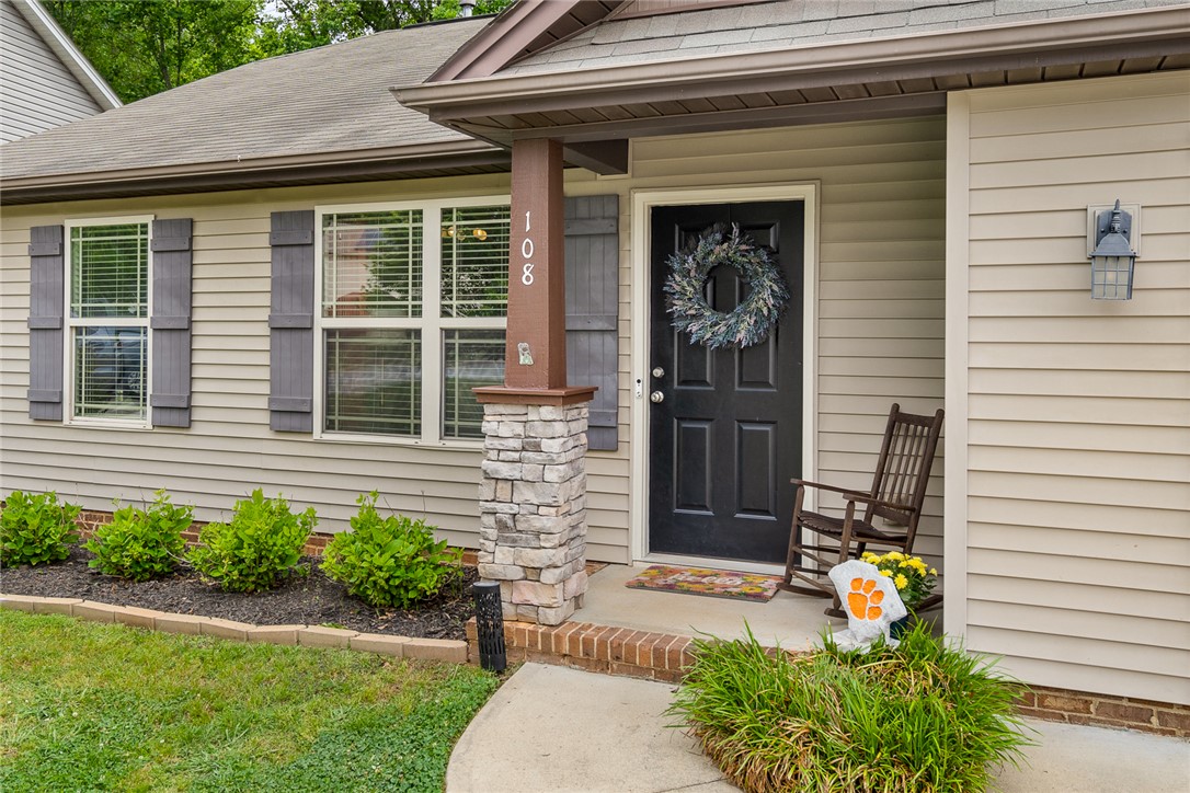 108 Belspring Lane Anderson, SC 29621 - Photo 3 of 19 The inviting entrance features a dark door, stone column, and vibrant landscaping.