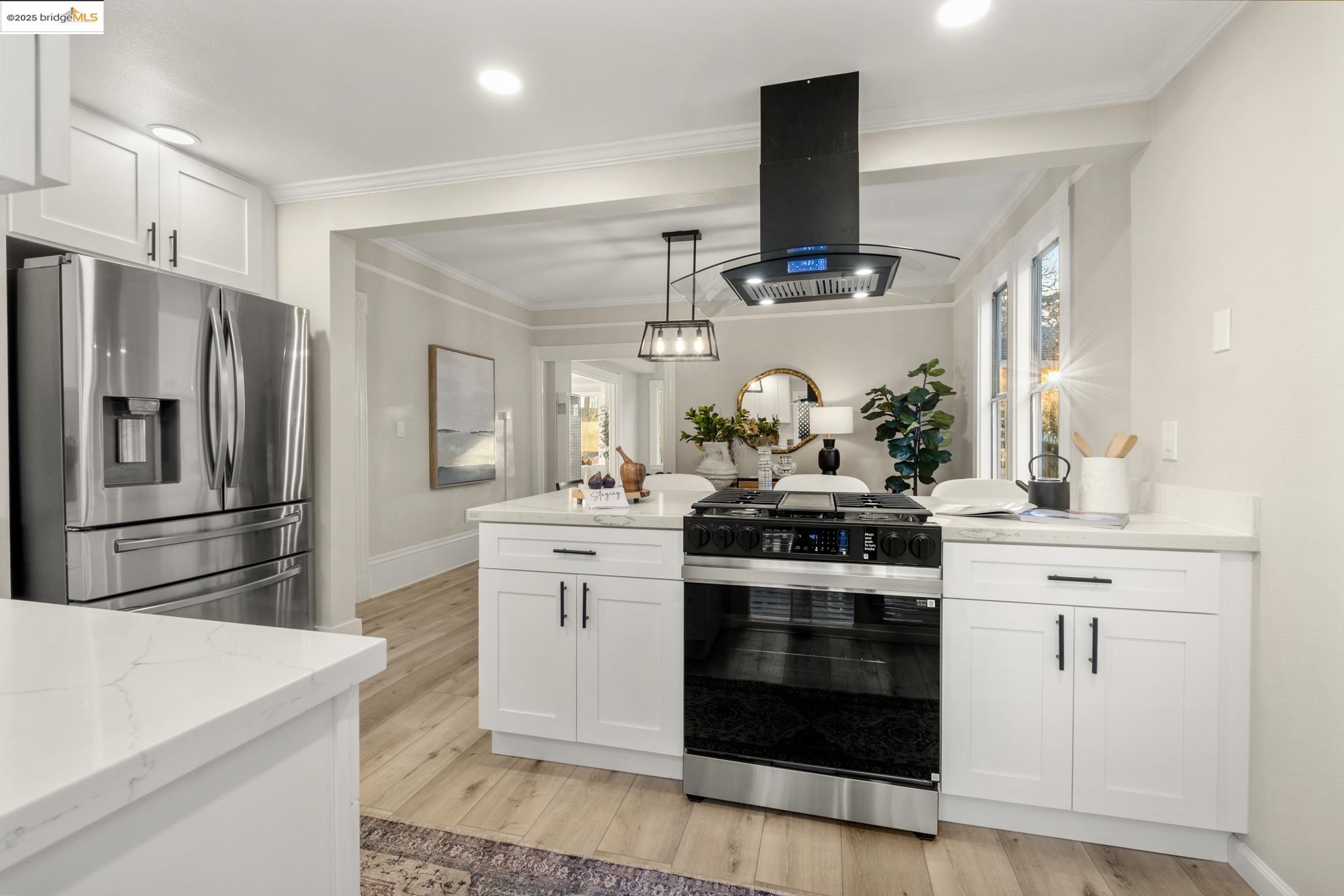 2050 East 30th Street Oakland, CA 94606 - Photo 15 of 48 Kitchen with gas stove, stainless steel fridge, island range hood, white cabinetry, and light stone countertops