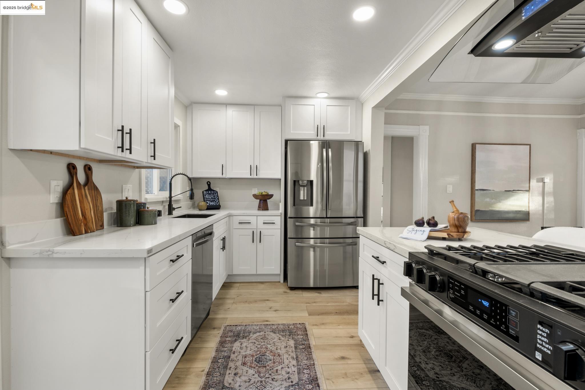 2050 East 30th Street Oakland, CA 94606 - Photo 16 of 48 Kitchen with appliances with stainless steel finishes, white cabinets, light stone counters, ornamental molding, and recessed lighting