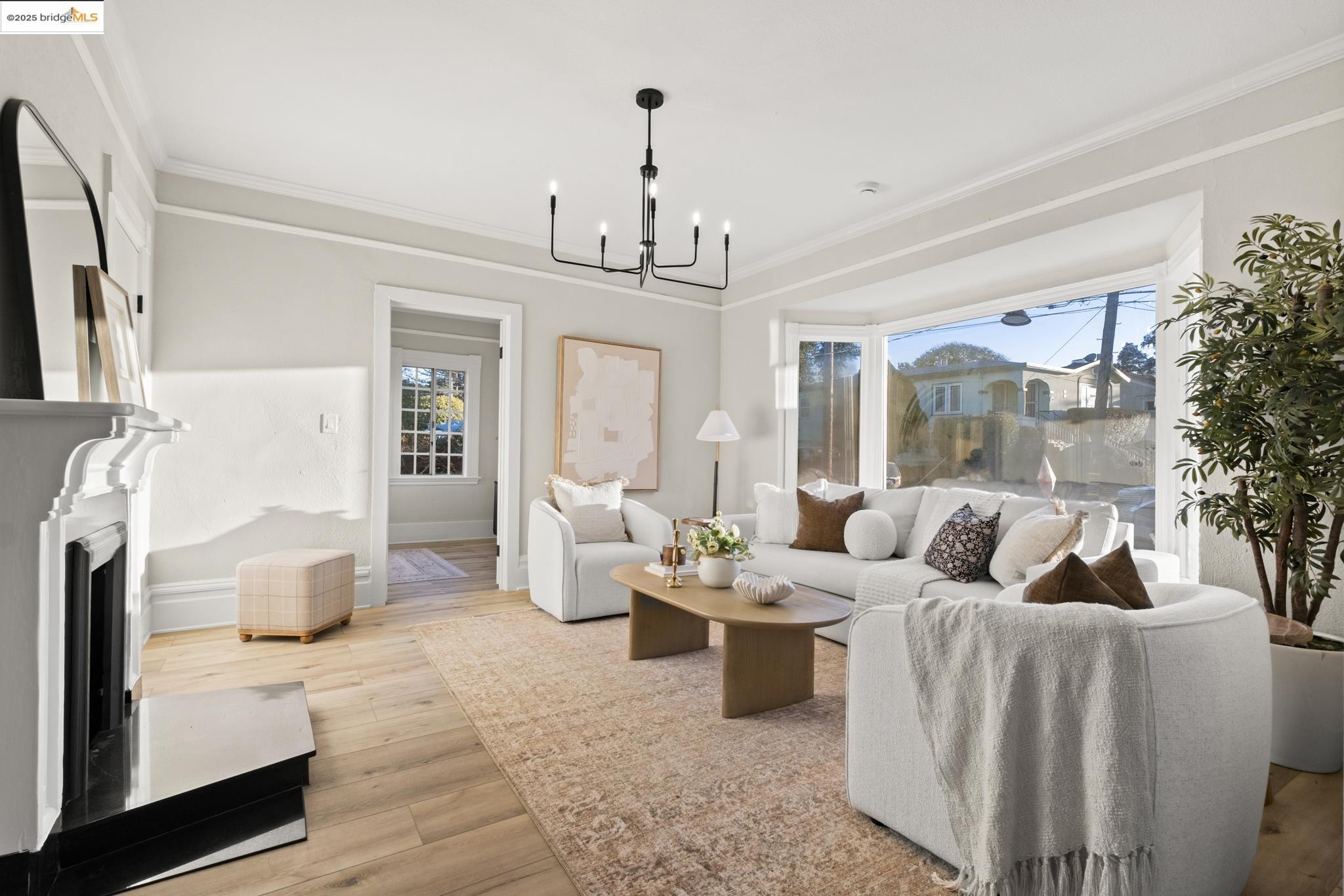 2050 East 30th Street Oakland, CA 94606 - Photo 2 of 48 Living room with light wood finished floors, a fireplace with raised hearth, crown molding, and a chandelier