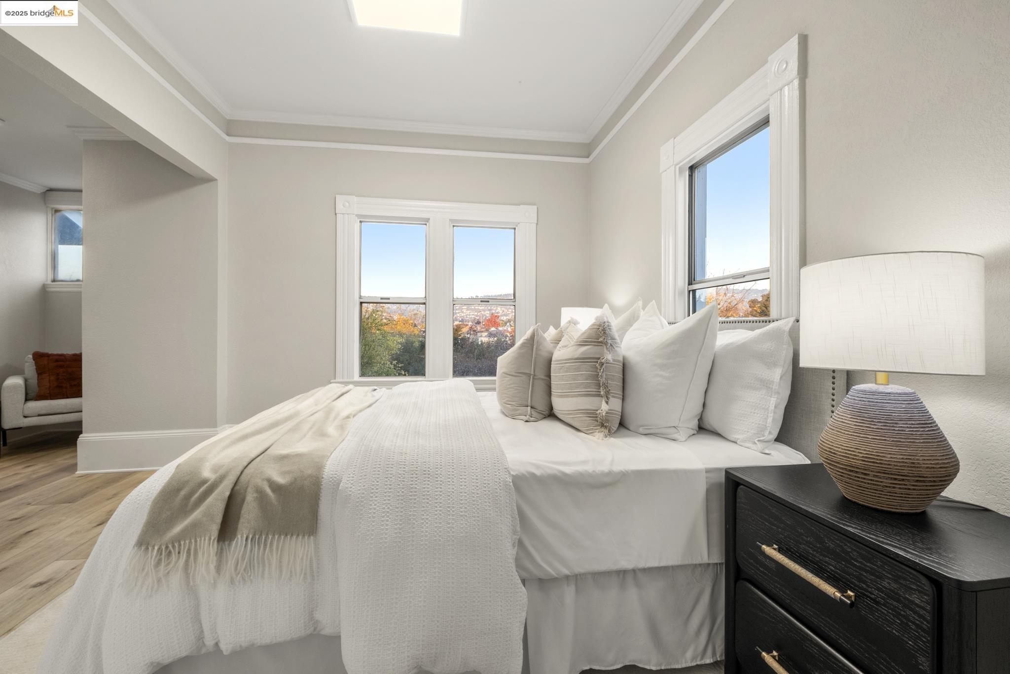 2050 East 30th Street Oakland, CA 94606 - Photo 23 of 48 Bedroom featuring ornamental molding, multiple windows, and light wood finished floors
