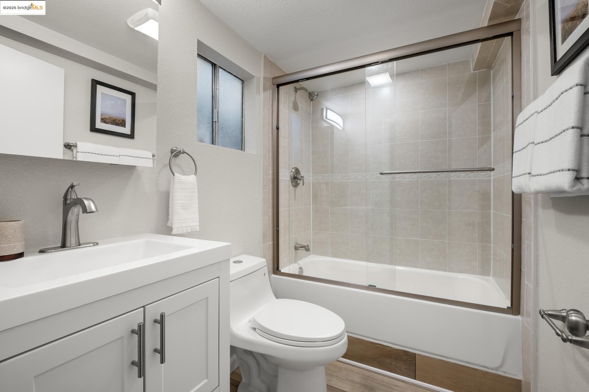 2050 East 30th Street Oakland, CA 94606 - Photo 39 of 48 Bathroom with vanity, bath / shower combo with glass door, and wood finished floors