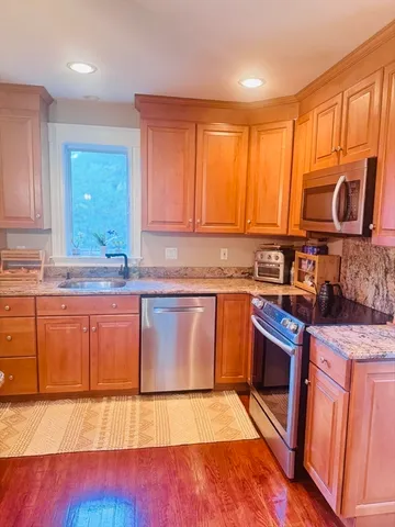 a kitchen with stainless steel appliances granite countertop a stove a sink and a microwave