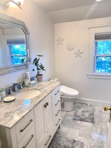 a bathroom with a granite countertop toilet sink and mirror