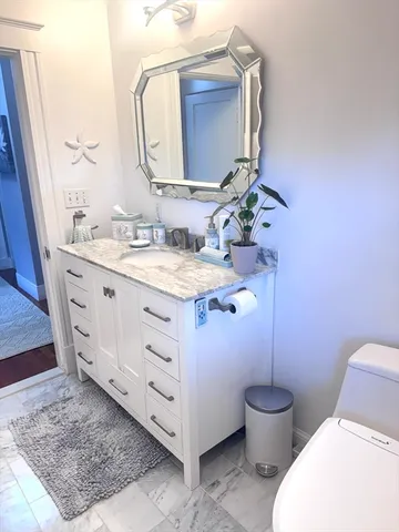 a bathroom with a granite countertop toilet sink and mirror