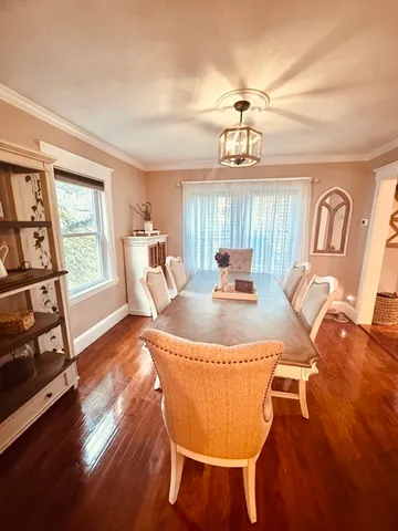 a dining room with wooden floor a chandelier a glass table and chairs