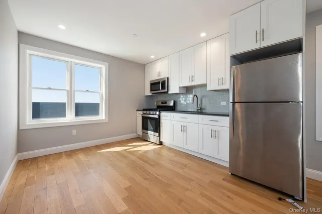 a kitchen with a refrigerator a stove top oven and white cabinets