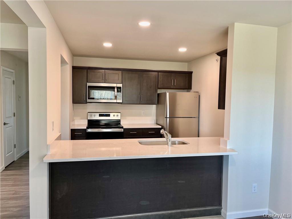 a kitchen with stainless steel appliances a refrigerator a sink a stove a microwave and island