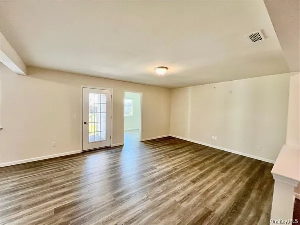 a view of an empty room with window and wooden floor
