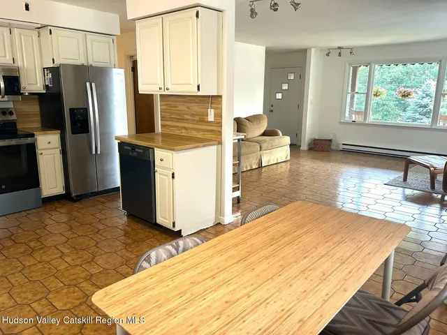 a kitchen with stainless steel appliances kitchen island granite countertop a refrigerator stove oven with white cabinets and wooden floor