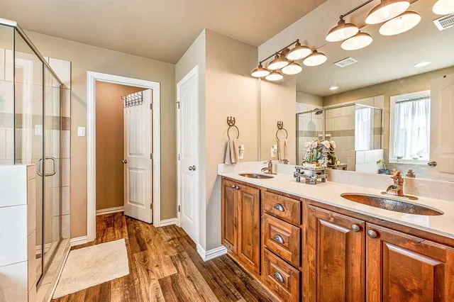 a spacious bathroom with a double vanity sink a mirror and a shower