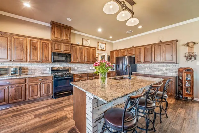 a kitchen with kitchen island granite countertop a stove cabinets and wooden floor