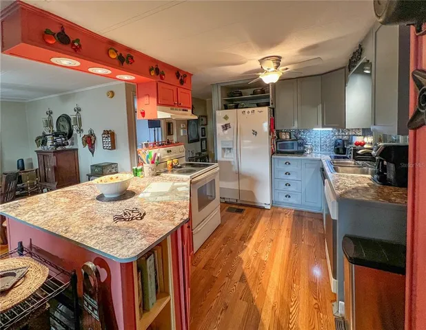 a kitchen that has a lot of cabinets a sink and a wooden floor