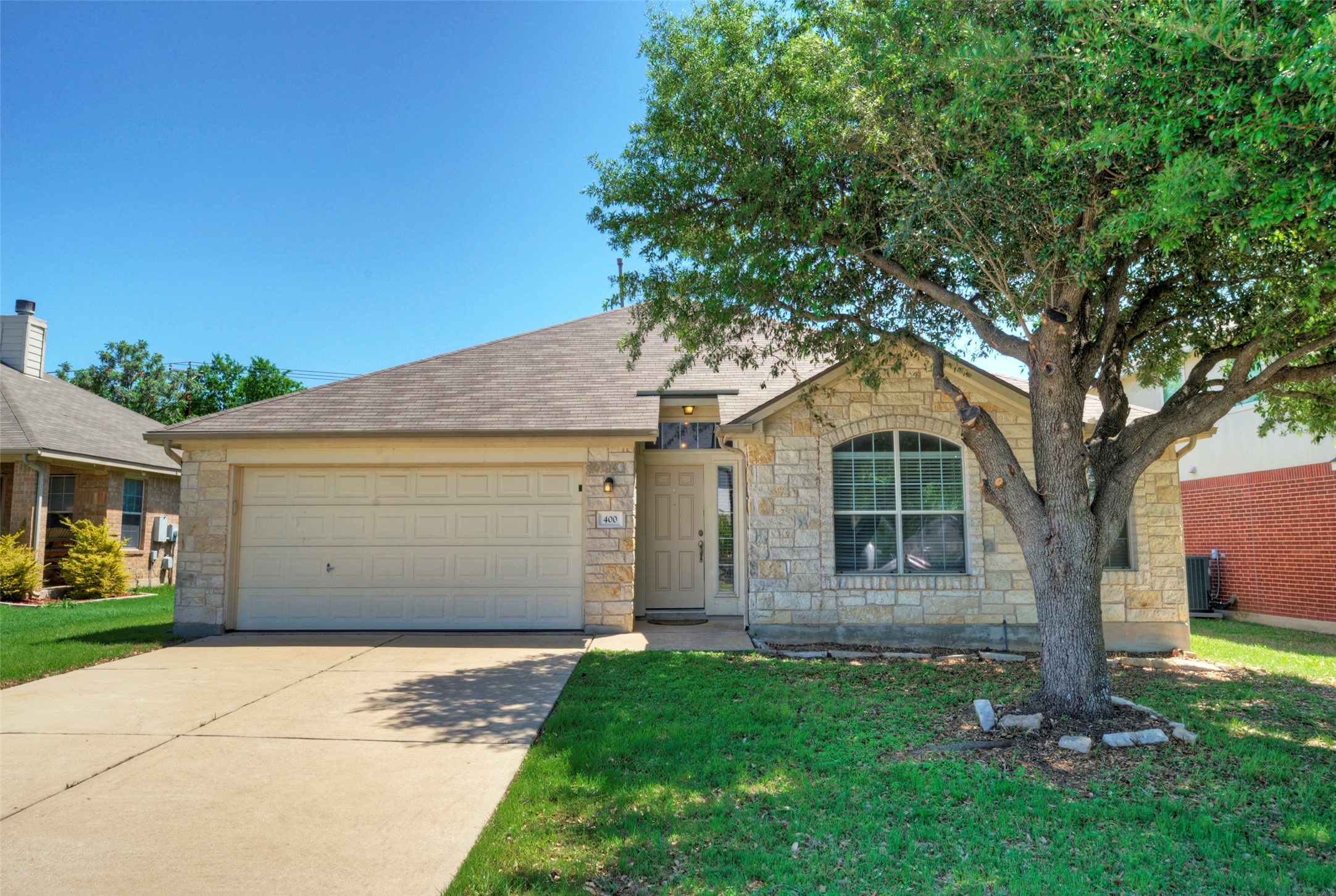 Stone facade home featuring an arched window, a two-car garage, and a concrete driveway