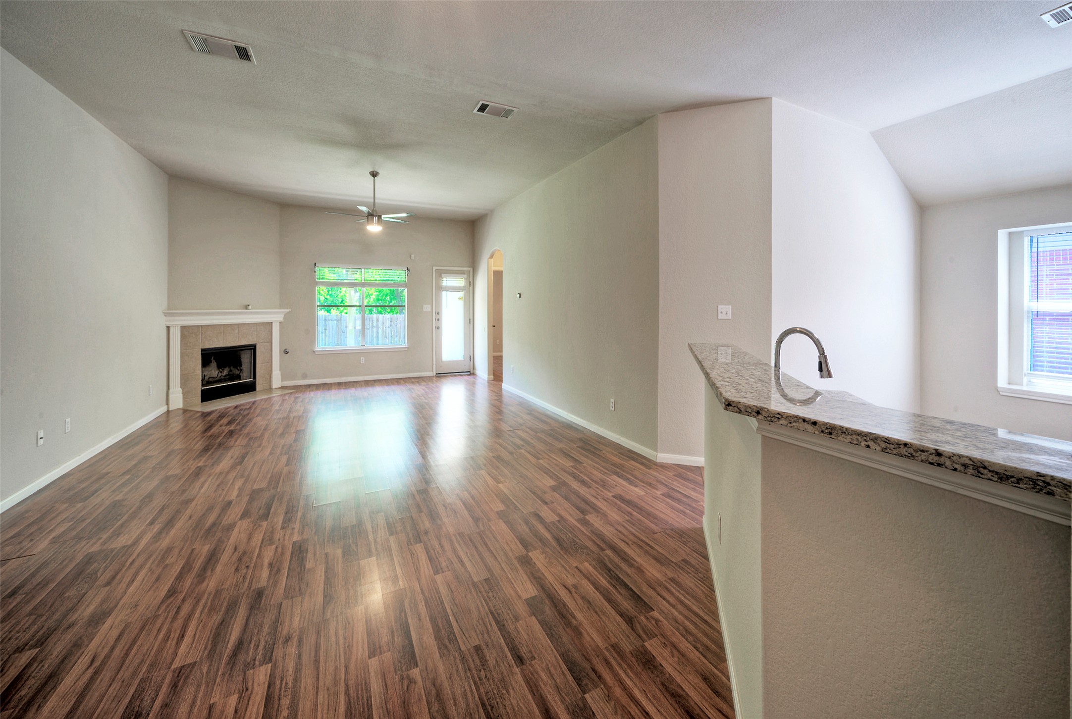 400 Pheasant Ridge Drive Round Rock, TX 78665 - Photo 11 of 29 Open concept living space featuring wood-finish flooring, a corner fireplace with a mantel, a ceiling fan, and a granite-topped breakfast bar