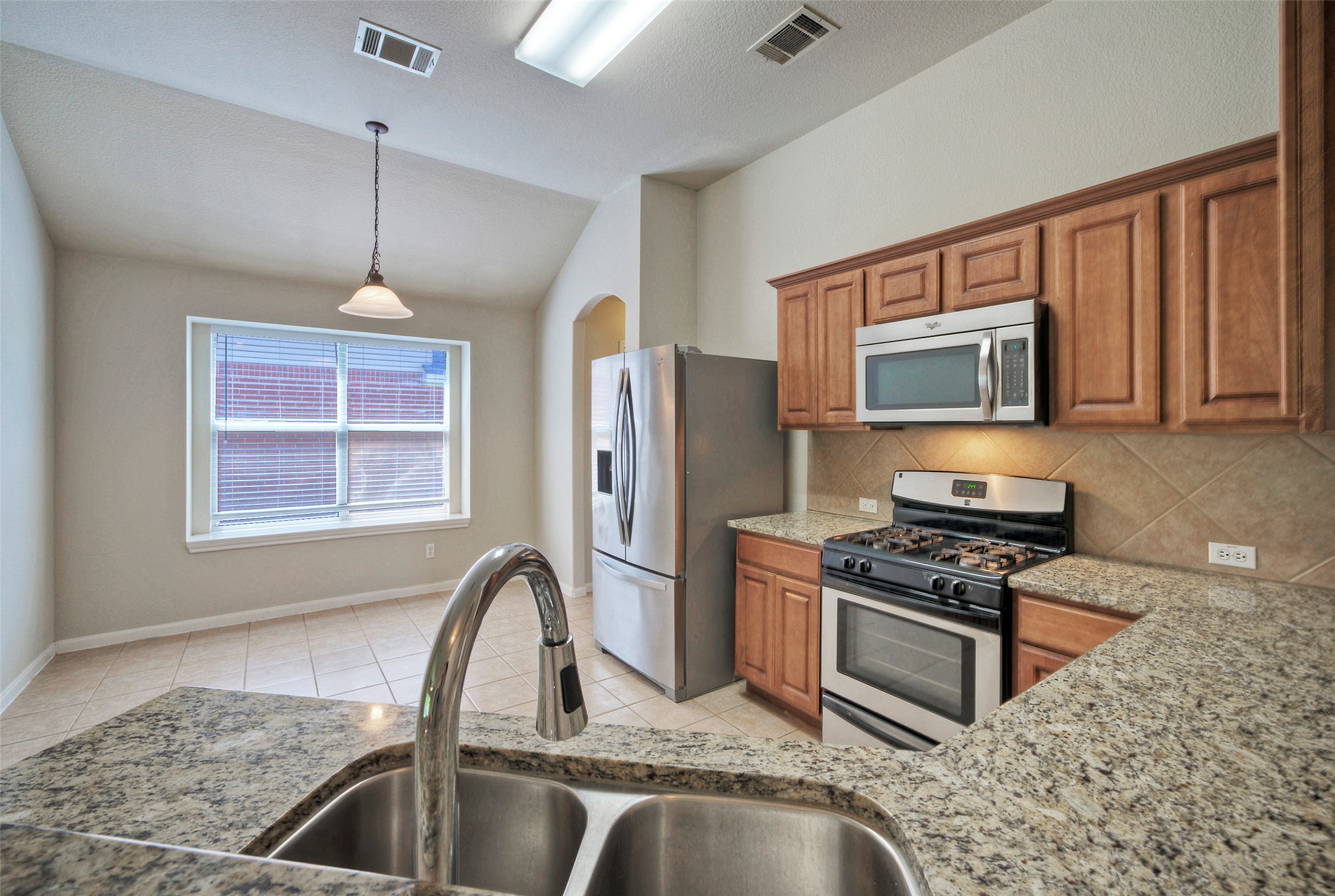 400 Pheasant Ridge Drive Round Rock, TX 78665 - Photo 18 of 29 Kitchen featuring granite countertops, wood cabinetry, stainless steel appliances, and a tile backsplash