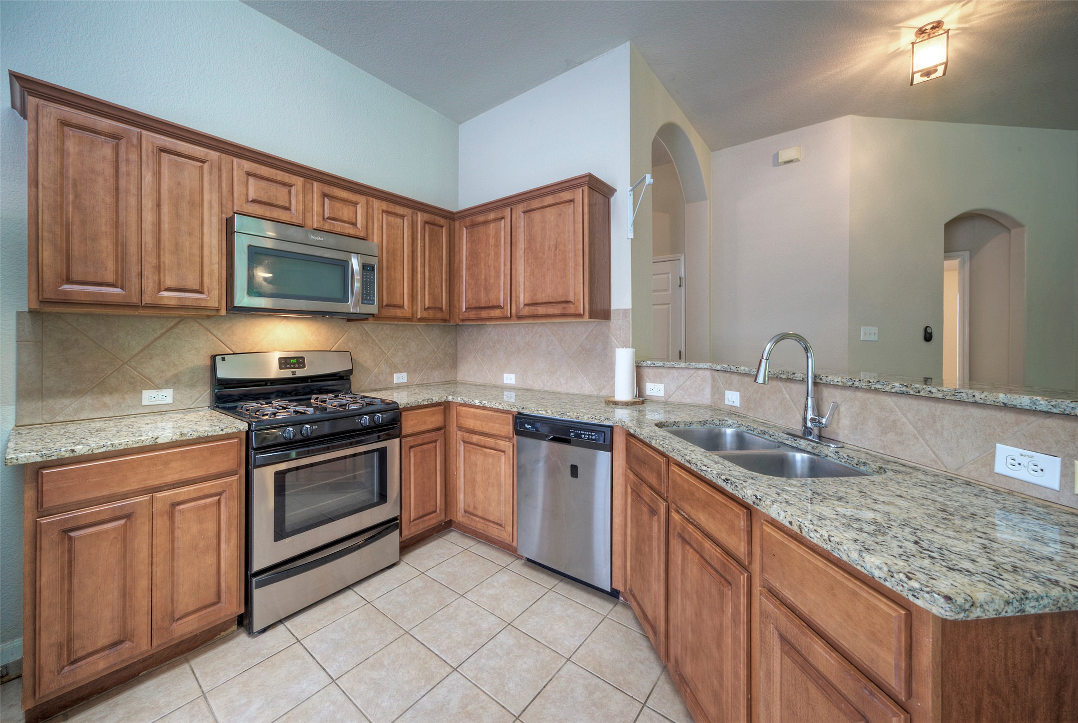 400 Pheasant Ridge Drive Round Rock, TX 78665 - Photo 20 of 29 Kitchen featuring light wood cabinetry, stainless steel appliances, granite countertops, tile backsplash, and tile flooring