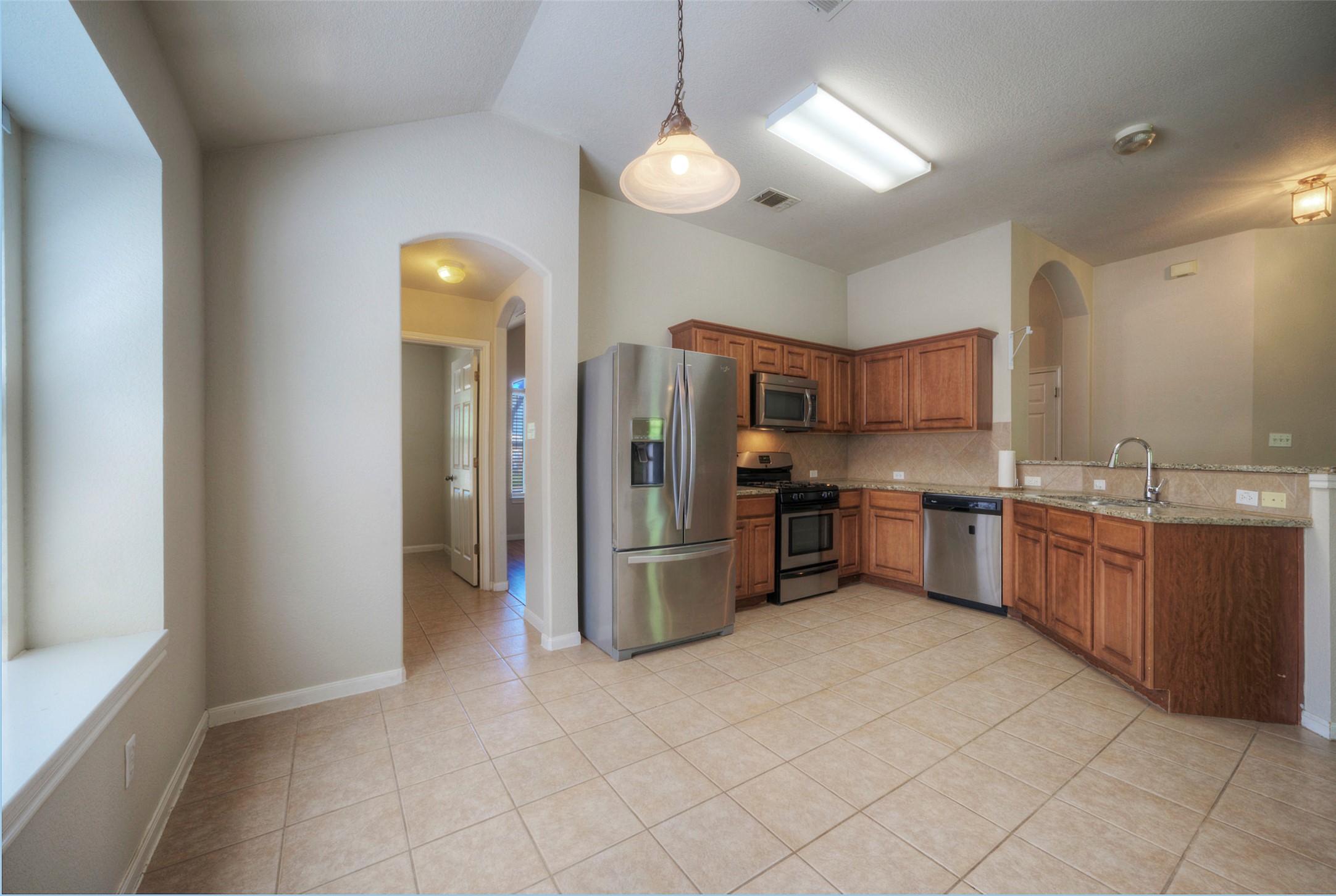 400 Pheasant Ridge Drive Round Rock, TX 78665 - Photo 21 of 29 Kitchen featuring wood cabinetry, stainless steel appliances, tile flooring, and a stone-finish countertop with a breakfast bar