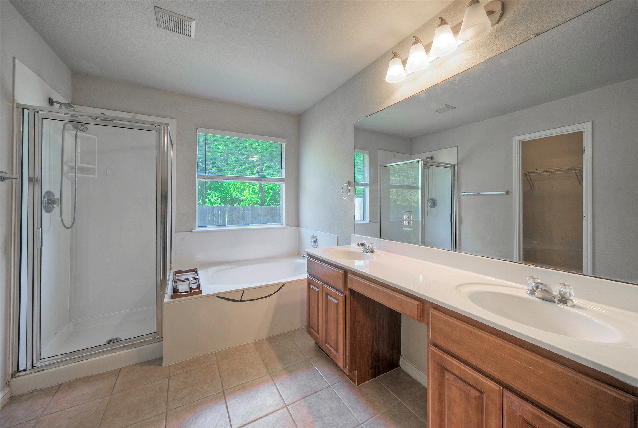 400 Pheasant Ridge Drive Round Rock, TX 78665 - Photo 26 of 29 Bathroom featuring a walk-in shower with glass enclosure, a large soaking tub, and a dual-sink vanity with wood cabinetry