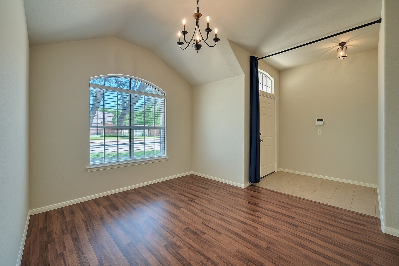 400 Pheasant Ridge Drive Round Rock, TX 78665 - Photo 9 of 29 Vaulted ceiling with a chandelier, arch-top window, wood-finish flooring, and a tiled entryway with a transom window