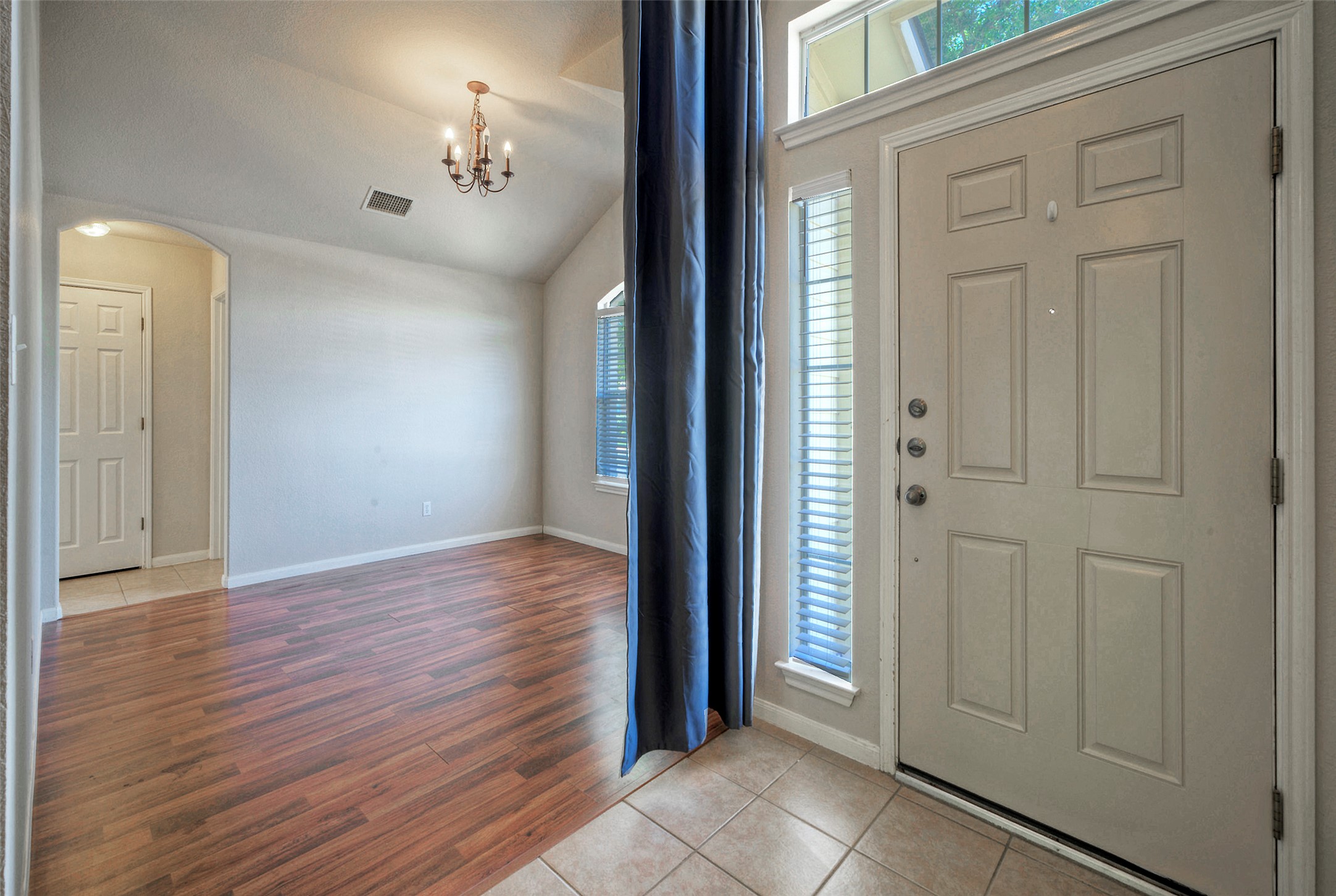 400 Pheasant Ridge Drive Round Rock, TX 78665 - Photo 10 of 29 Entry foyer with light tile flooring opens to a living area featuring wood-finish flooring, vaulted ceiling, and an ornate chandelier