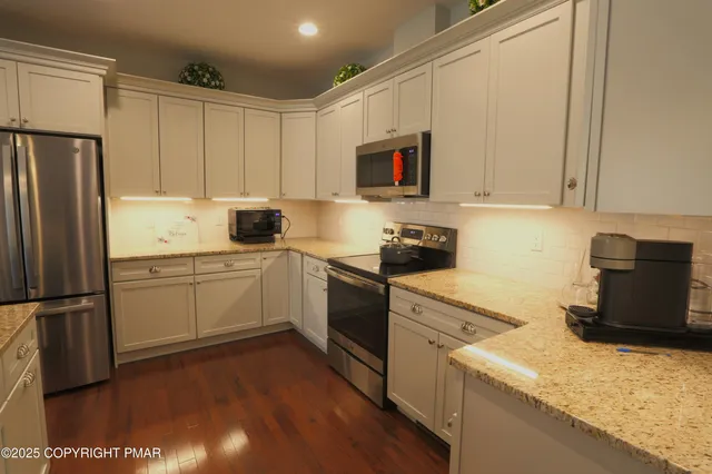 a kitchen with granite countertop a refrigerator sink and white cabinets