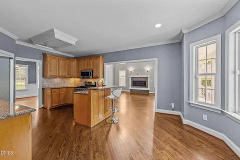 a kitchen with stainless steel appliances granite countertop wooden floors a stove top oven a granite counter space and a window