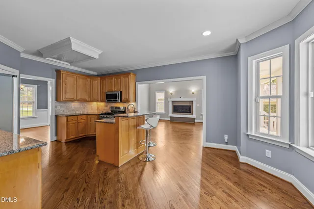 a kitchen with stainless steel appliances granite countertop wooden floors a stove top oven a granite counter space and a window