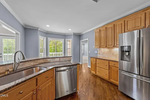 a kitchen with granite countertop stainless steel appliances a refrigerator sink and wooden cabinets