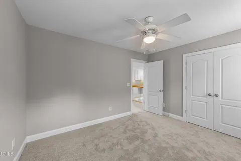 an empty room with closet and a ceiling fan