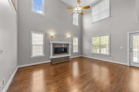an empty room with wooden floor fireplace and windows