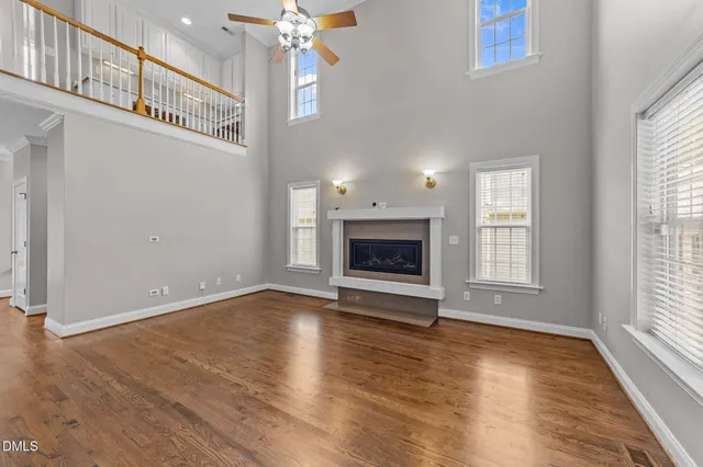 an empty room with wooden floor fireplace and windows