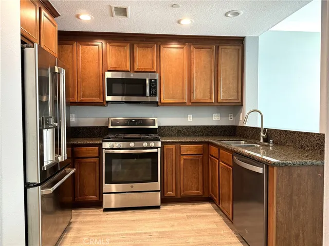 a kitchen with stainless steel appliances granite countertop a stove a sink and a microwave