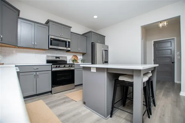 a kitchen with stainless steel appliances a sink a stove a refrigerator cabinets and a window