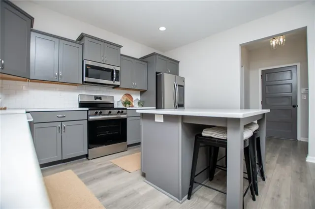 a kitchen with stainless steel appliances a sink a stove a refrigerator cabinets and a window