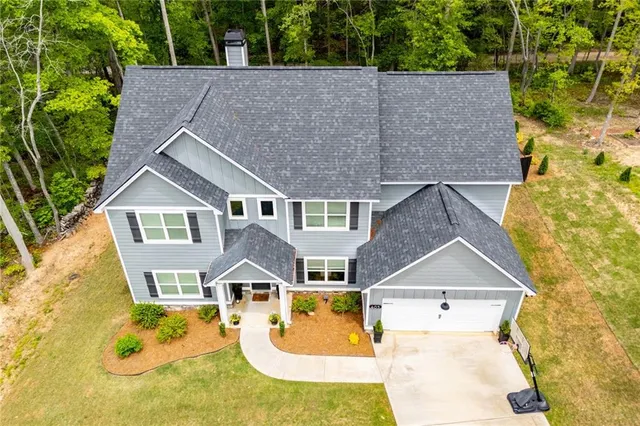 a view of a house with a big yard and large trees