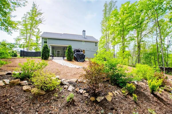 a view of a house with lots of plants and a large tree