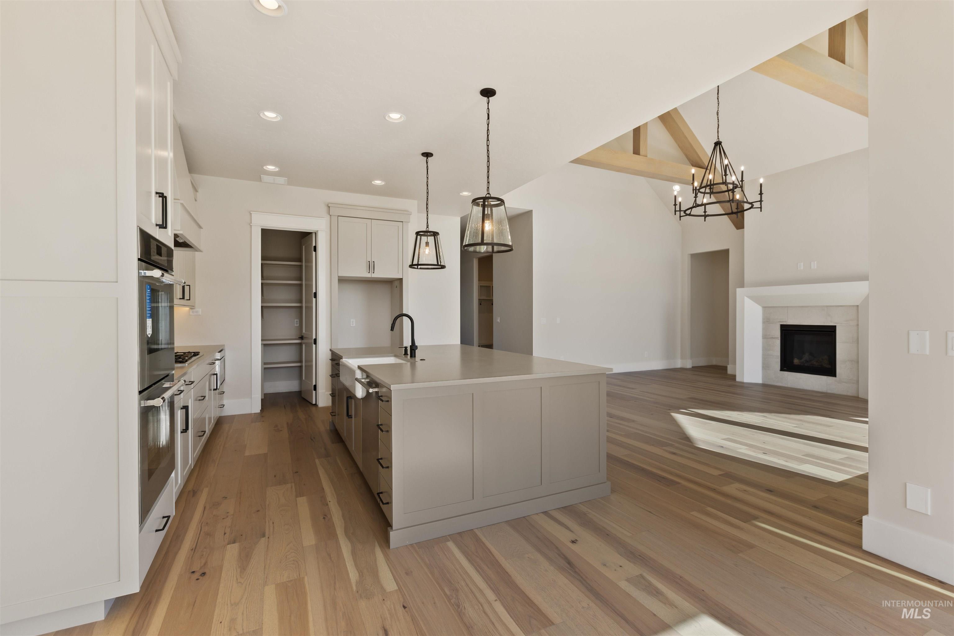 5857 South Highmark Avenue Meridian, ID 83642 - Photo 11 of 37 Kitchen with light wood finished floors, white cabinetry, a chandelier, recessed lighting, and hanging light fixtures