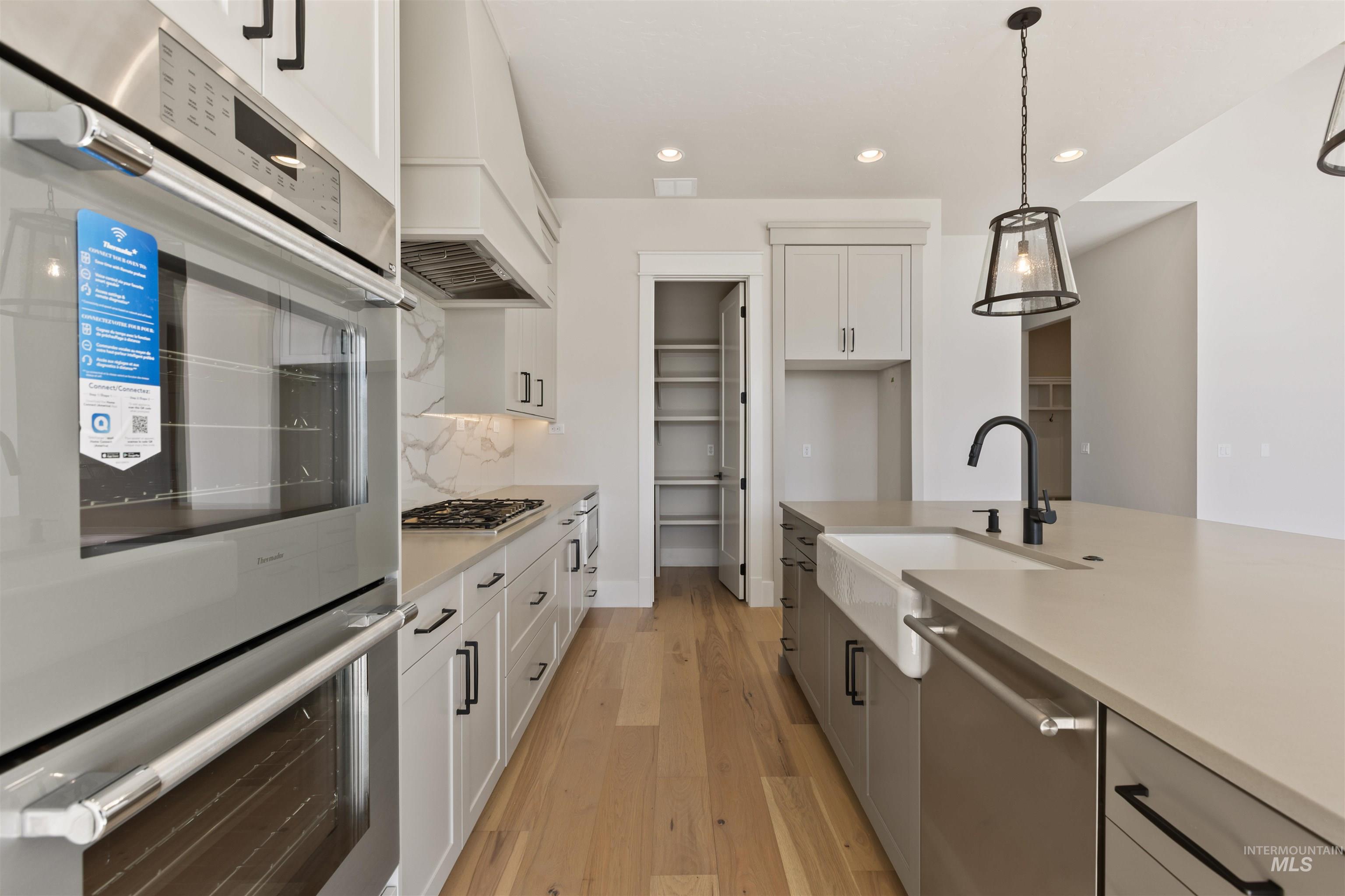 5857 South Highmark Avenue Meridian, ID 83642 - Photo 12 of 37 Kitchen with appliances with stainless steel finishes, pendant lighting, light countertops, light wood finished floors, and recessed lighting