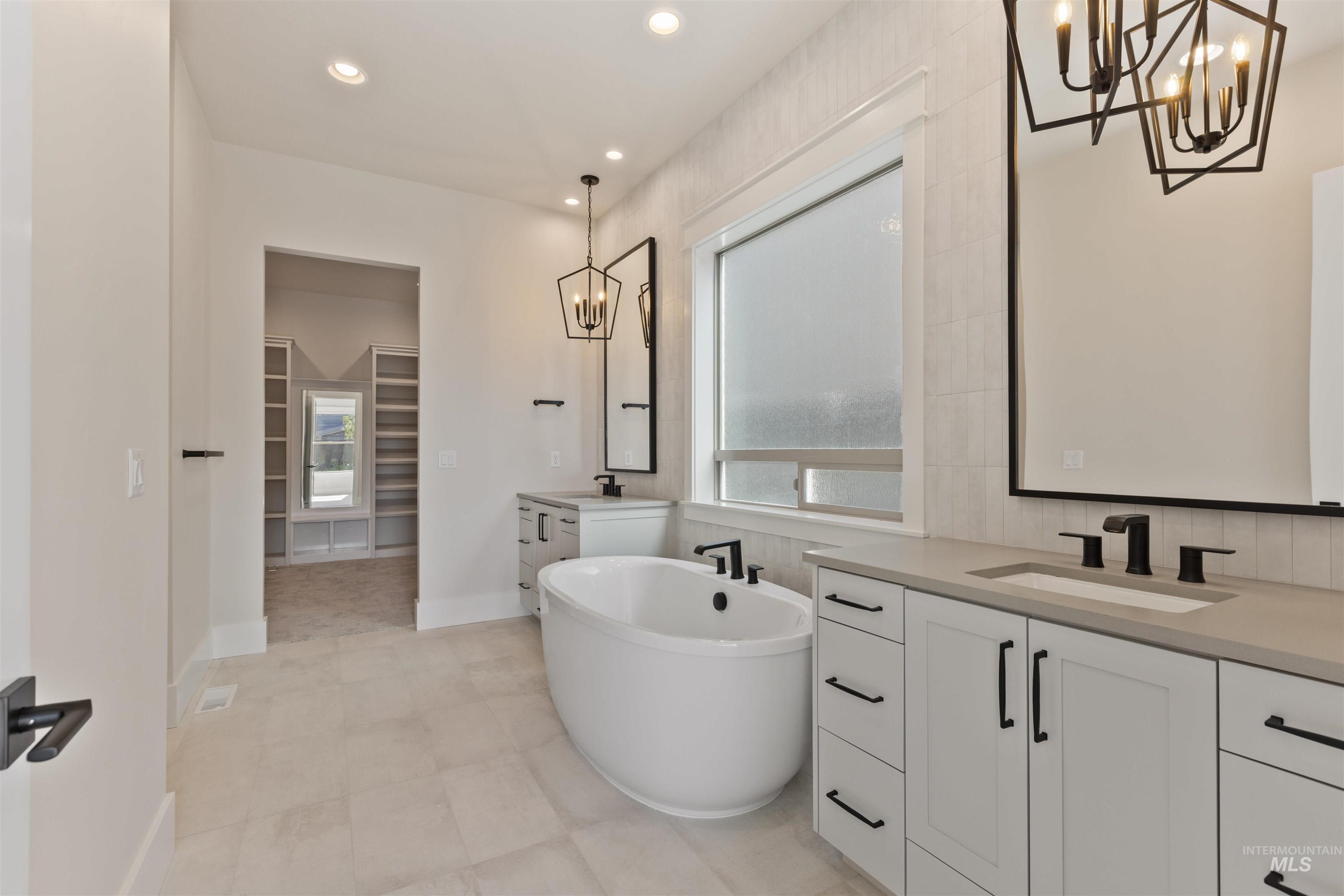 5857 South Highmark Avenue Meridian, ID 83642 - Photo 17 of 37 Full bath with a chandelier, two vanities, a spacious closet, a soaking tub, and recessed lighting