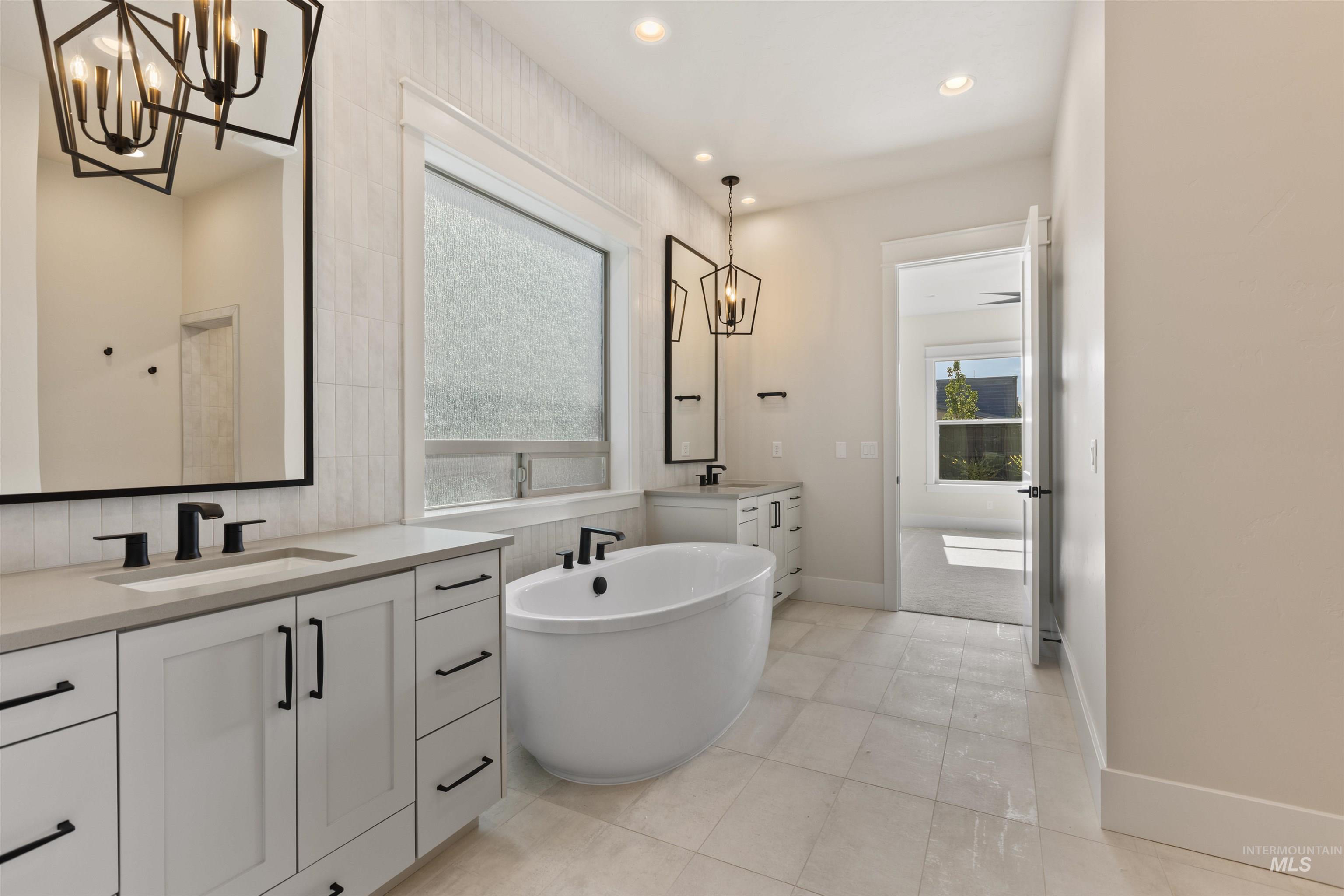 5857 South Highmark Avenue Meridian, ID 83642 - Photo 19 of 37 Bathroom featuring a chandelier, two vanities, a freestanding bath, tile patterned floors, and recessed lighting