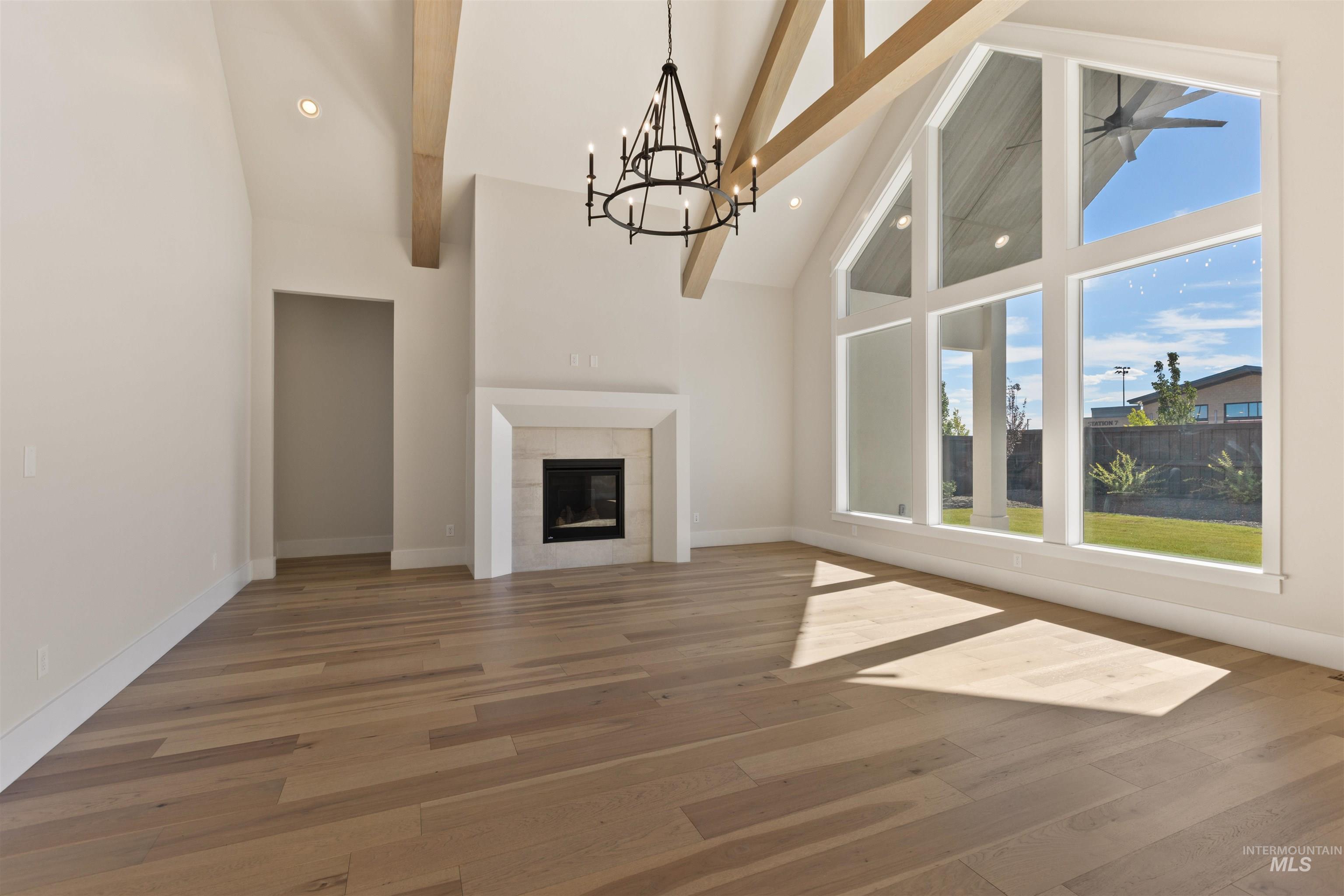 5857 South Highmark Avenue Meridian, ID 83642 - Photo 3 of 37 Unfurnished living room with high vaulted ceiling, a chandelier, beam ceiling, wood finished floors, and recessed lighting