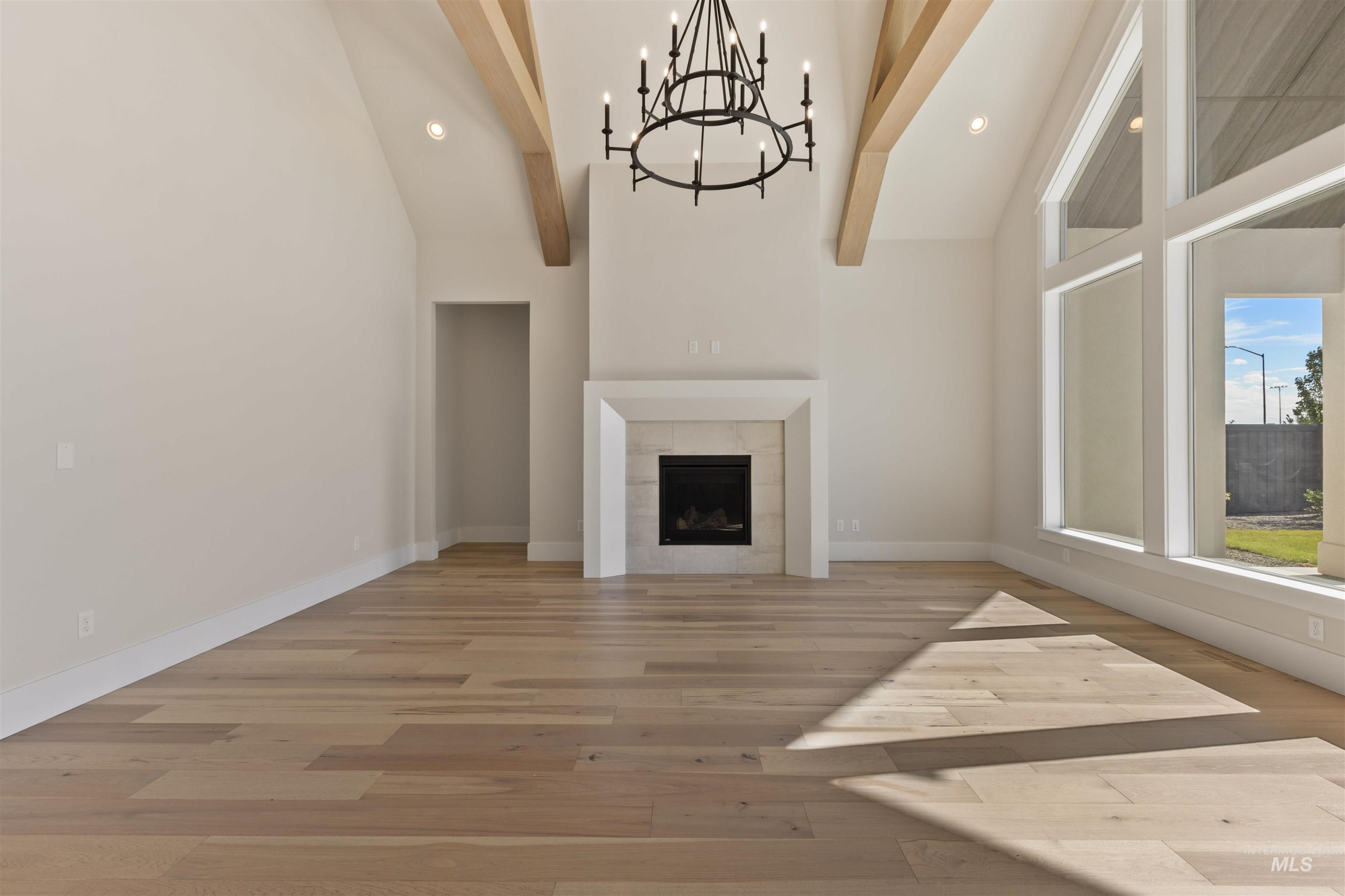 5857 South Highmark Avenue Meridian, ID 83642 - Photo 4 of 37 Unfurnished living room featuring light wood finished floors, a chandelier, beam ceiling, high vaulted ceiling, and recessed lighting